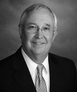 headshot of man with glasses and wearing a business suit