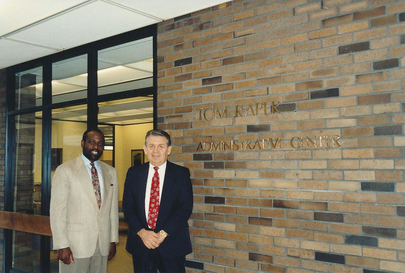 Two men standing next to each other next to a sign that says Tom Raper Administrative Services