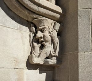 Stone carving of a professor angrily ringing a bell.