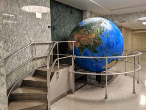 Photo of a large globe inside a building. A short filght of stairs leads up to viewing platform next to the globe.