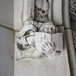 Carving of a figure reading a book.