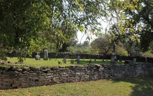 Photo of a small cemetery surrounded by a limestone wall.