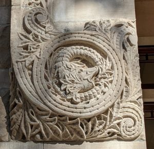 A coiled stone serpent carved into the side of a building.