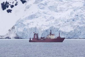 A large ship in front of a glacier