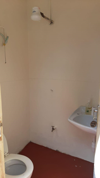 A bathroom with a toilet, sink and shower head on the wall to the left of the sink