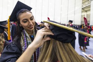 Graduates help one another get ready during the IU South Bend Commencement at the Joyce Center.