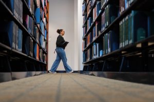 A student walks through a stack of books in the library at the Robert H. McKinney School of Law.