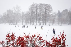 Students play football in the snow in Dunn Meadow at Indiana University Bloomington.