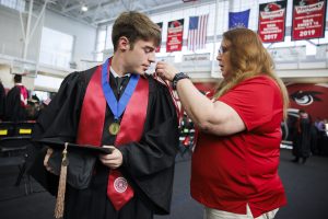 A graduate gets a hand with his honor cords before the IU Northwest Commencement.