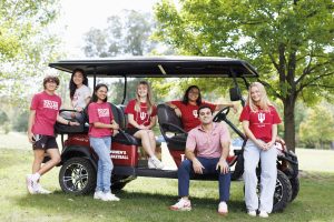 IU Bloomington students pose while riding a golf cart around the campus.