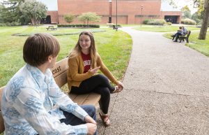 IU Southeast students chatting on a bench on campus.