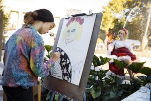 An artist draws a model near Showalter Fountain.