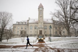 A student runs past the Student Building on a snowy winter day at IU Bloomington.