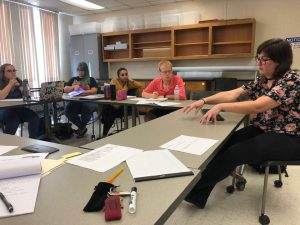 people seated around tables in a classroom setting.