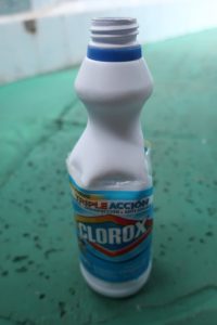 white plastic Clorox bottle about 8.5 inches tall. Clorox label still present, writing is visible, discernable, and in Spanish