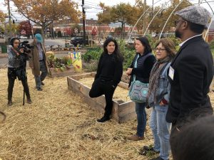 A group of people standing around raised beds and learning about an urban agriculture project.