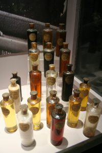 glass bottles ifilled with different colors of shale oil on display n a museum case.