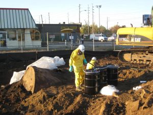 Two people in yellow hazmat gear excavate failing underground storage tanks at the Tuchman Cleaner's site in Indianapolis.