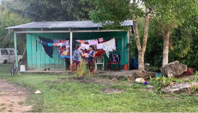 A photo of two people talking in front of a house.