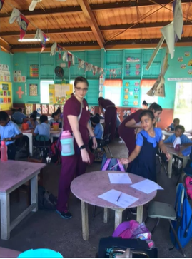 A photo of a classroom full of children with a nursing student.