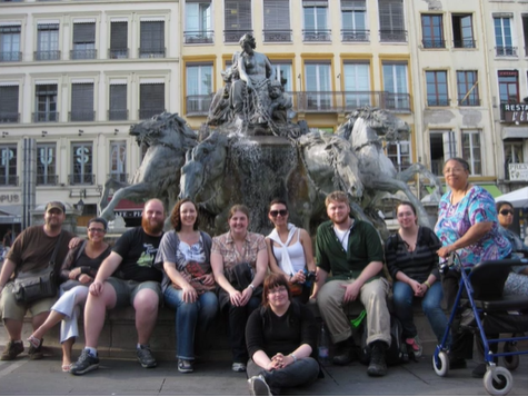 A photo of a group of people posing in front of a fountain.