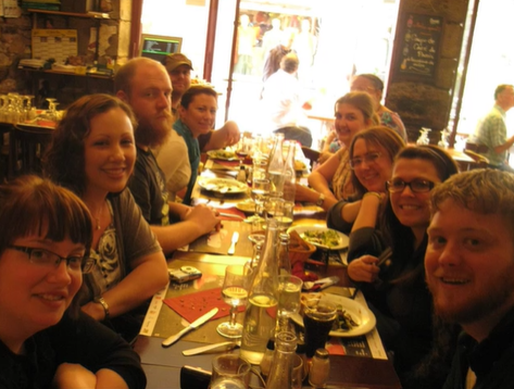 A photo of a group of people posing at a table in a restaurant.