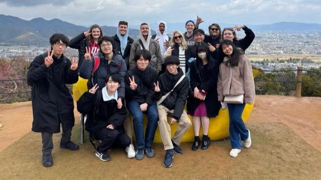 A photo of a group of people posing sitting on and around a banana bench.