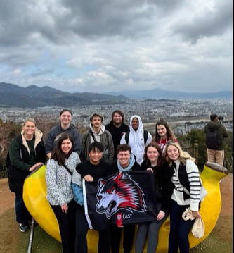 A photo of a group of people posing sitting on a banana bench.