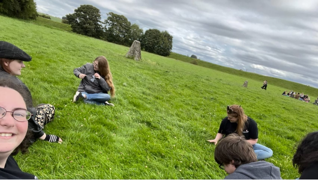 A photo of six people sitting in a field.