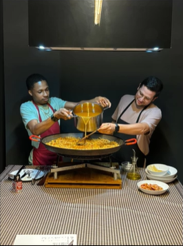 A photo of two people making paella.