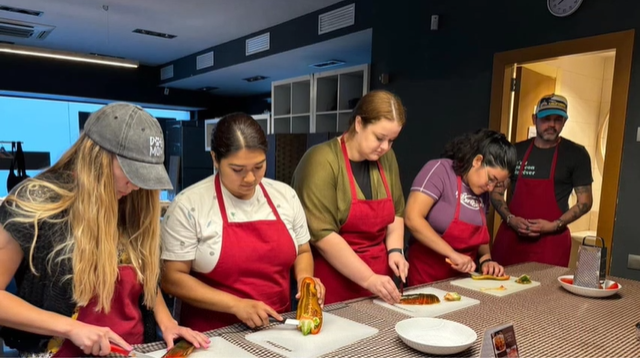 A photo of five people cooking.