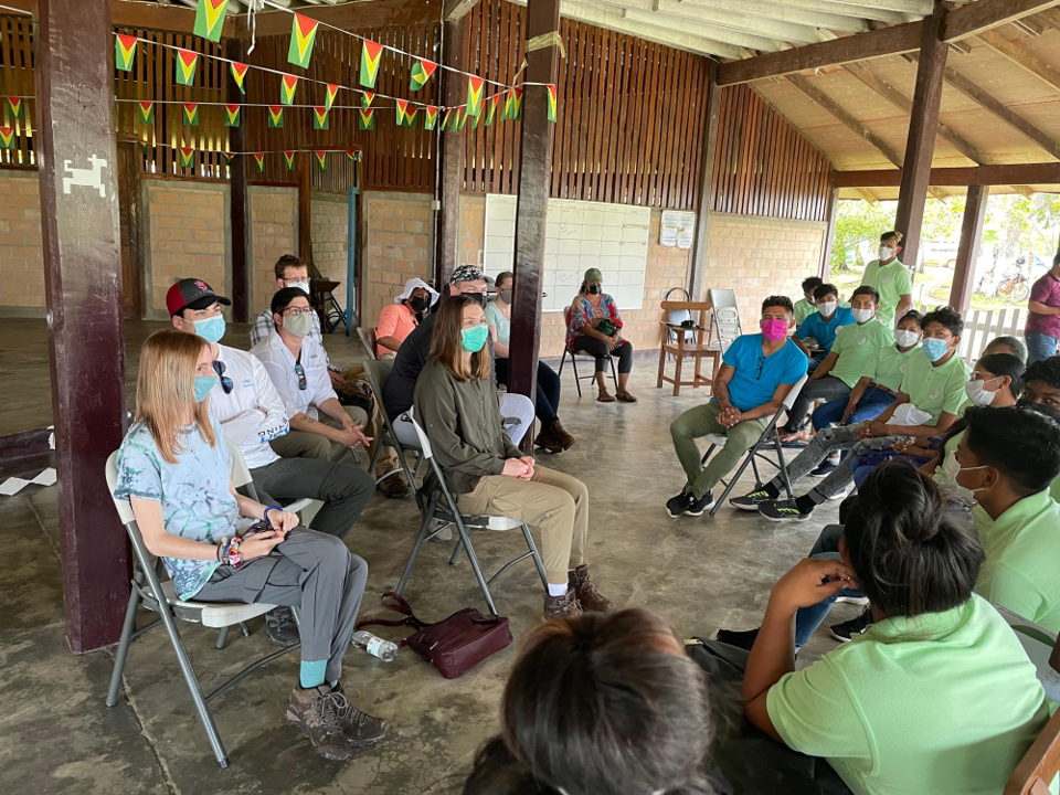 A group of people conversing sitting in a semi circle.