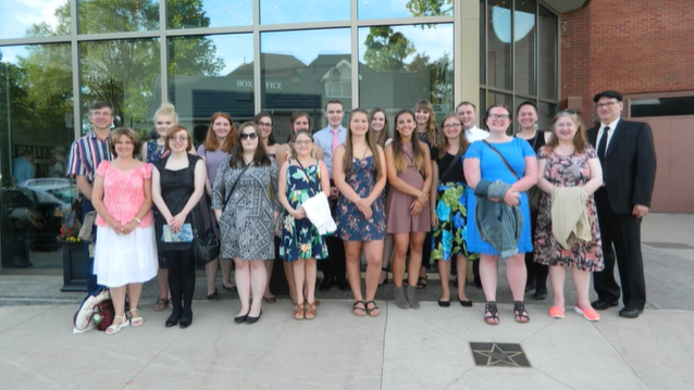 A photo of a group of people posing outside a building.