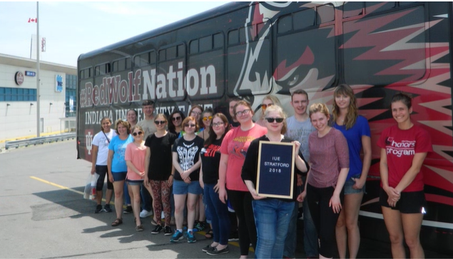 A photo of a group of people posing in front of a bus.