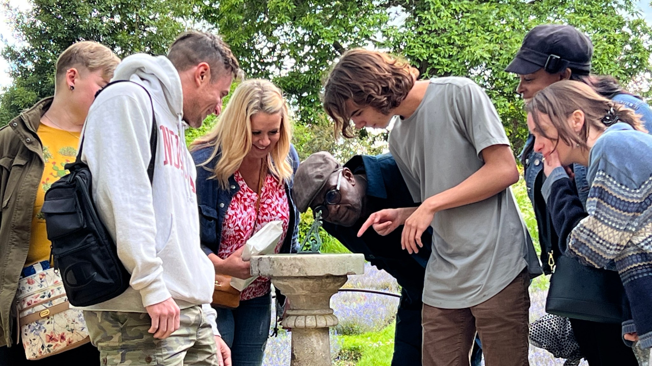 A photo of a group of people looking at a sun dial.