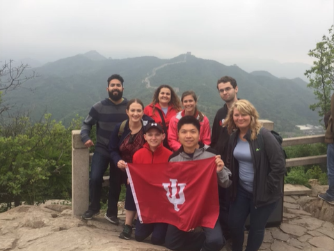 A photo of a group of people posing with a "Indiana University" flag.