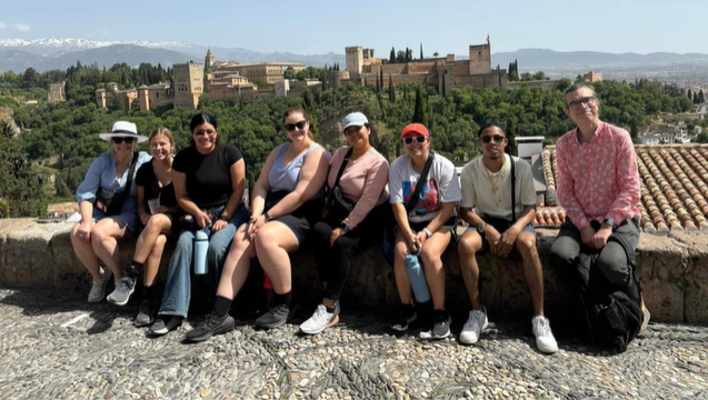 A photo of a group of people posing with a city in the background.