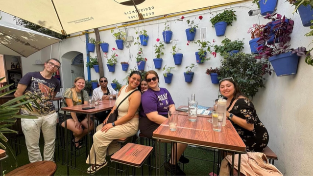 A photo of a group of people posing at tables in a café.