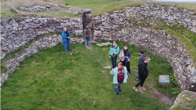 A one photo of seven people standing in an ancient Scottish residence.