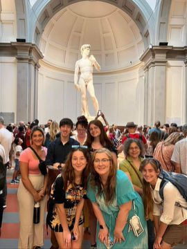 A photo of a group of people posing in front of David of Michelangelo.