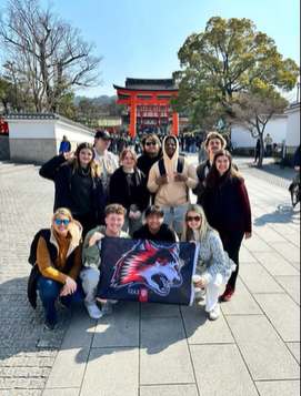 A photo of a group of people posing with a Torii in the background.