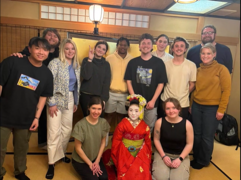 A photo of a group of people posing with a geisha.