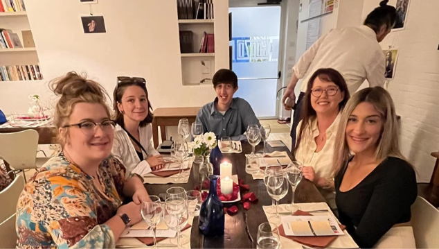 A photo of five people sitting at a table posing.