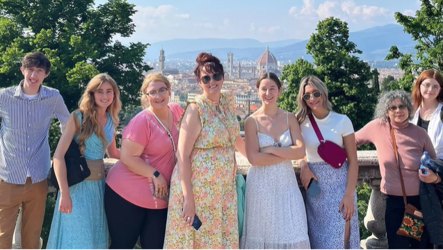 A photo of a group of people posing with a city in the background.