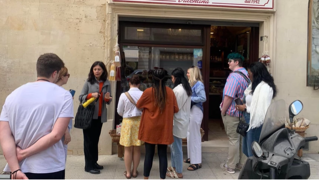 A photo of a group of people in front of a shop.