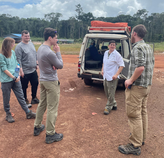 Image of five people standing next to a car on Linden-Lethem Road.