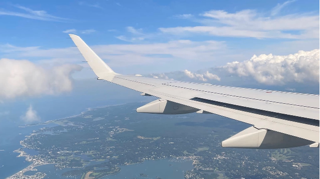 A photo of an airplane wing during take off with a city underneath the clouds.