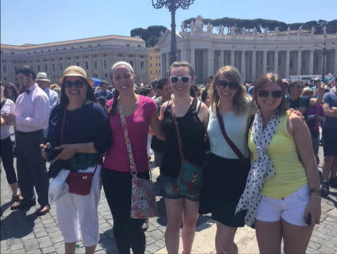 A photo of a group of people posing in front of buildings.