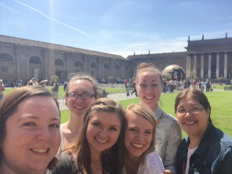 A photo of a group of people posing for a selfie in a courtyard.