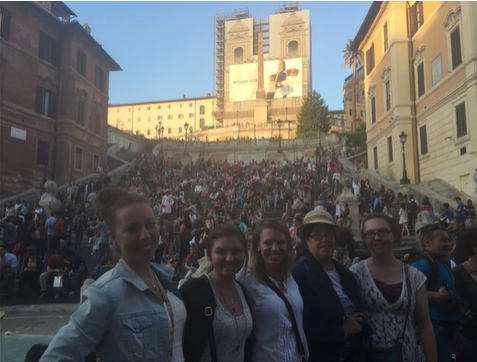 A photo of a group of people posing in front of a staircase.